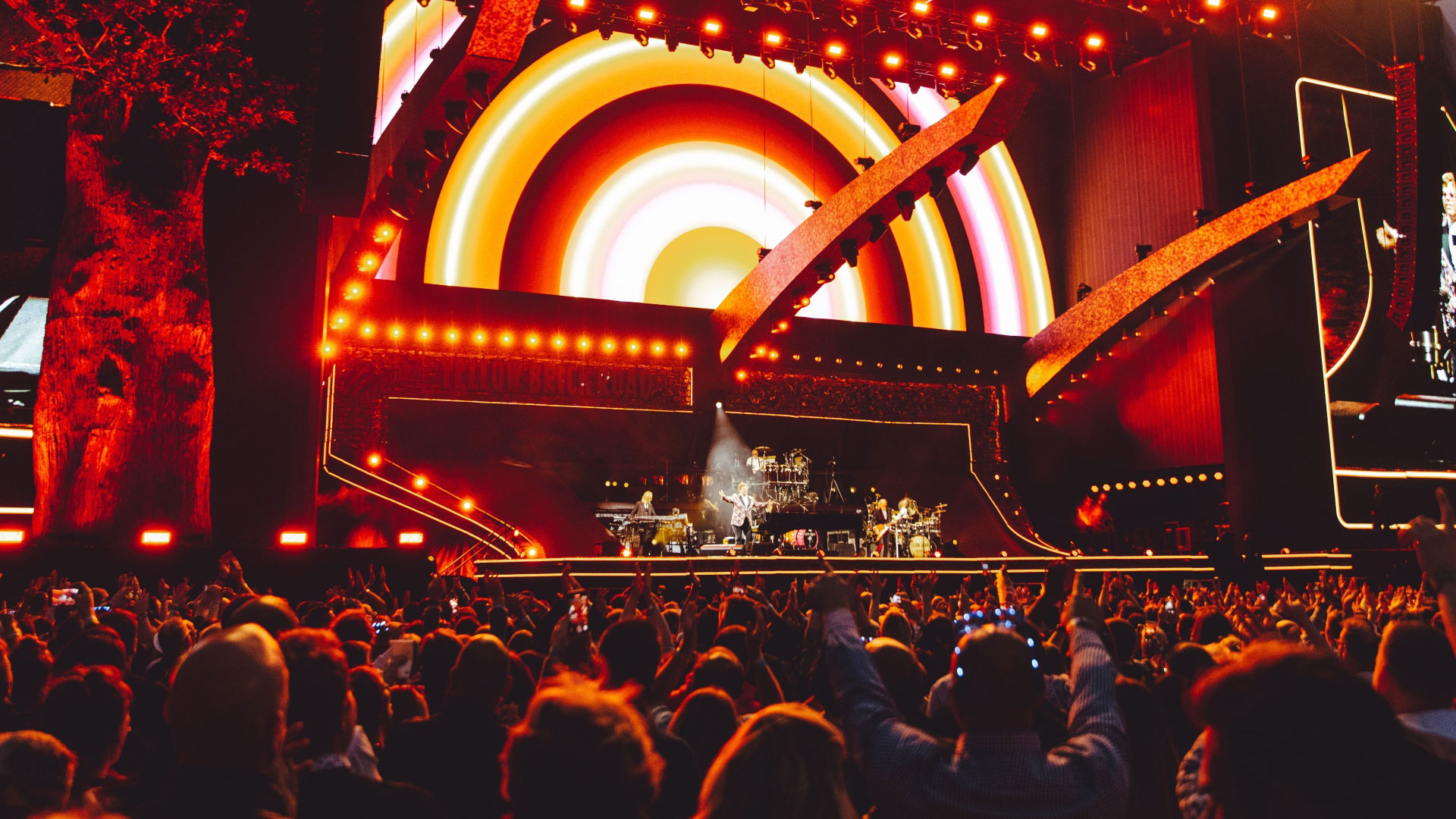 A photo from the crowd of the stage at Hyde Park British Summertime with bright orange coloured lights and visuals on the screens forming the backdrop of the stage