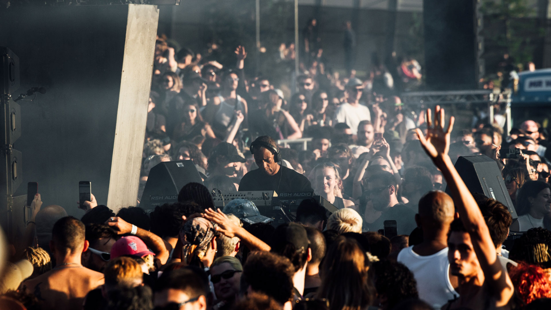 A photo of DJ, Jeff Mills, with headphones on and DJ equipment surrounded by hundreds of people dressed in festival outfits at Maiden Voyage festival 