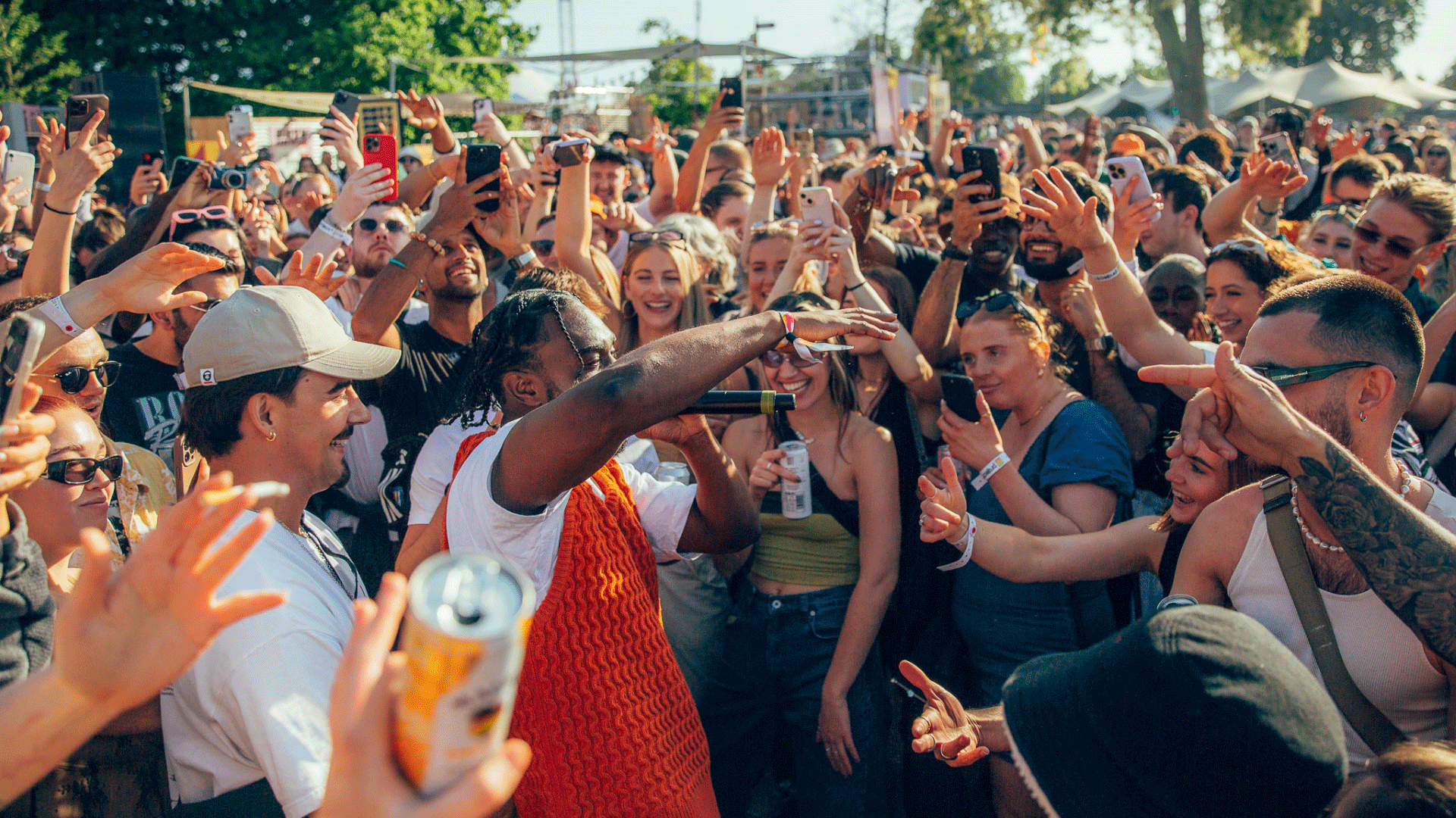 Crowds throwing their hands up in the air and singing along while the artist sings in the crowd