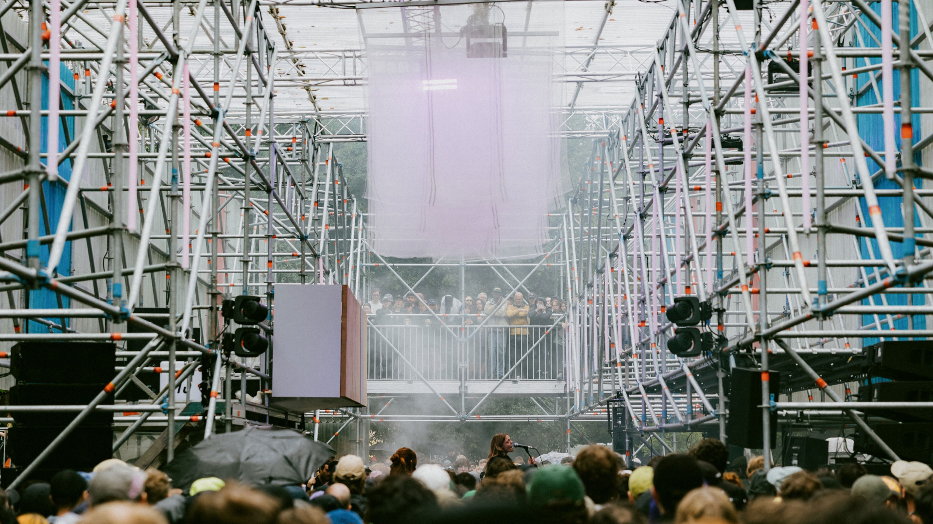 A photo of a stage at Rally festival made from scaffolding with crowds in the middle of the structure and a woman singing into a microphone on a stage