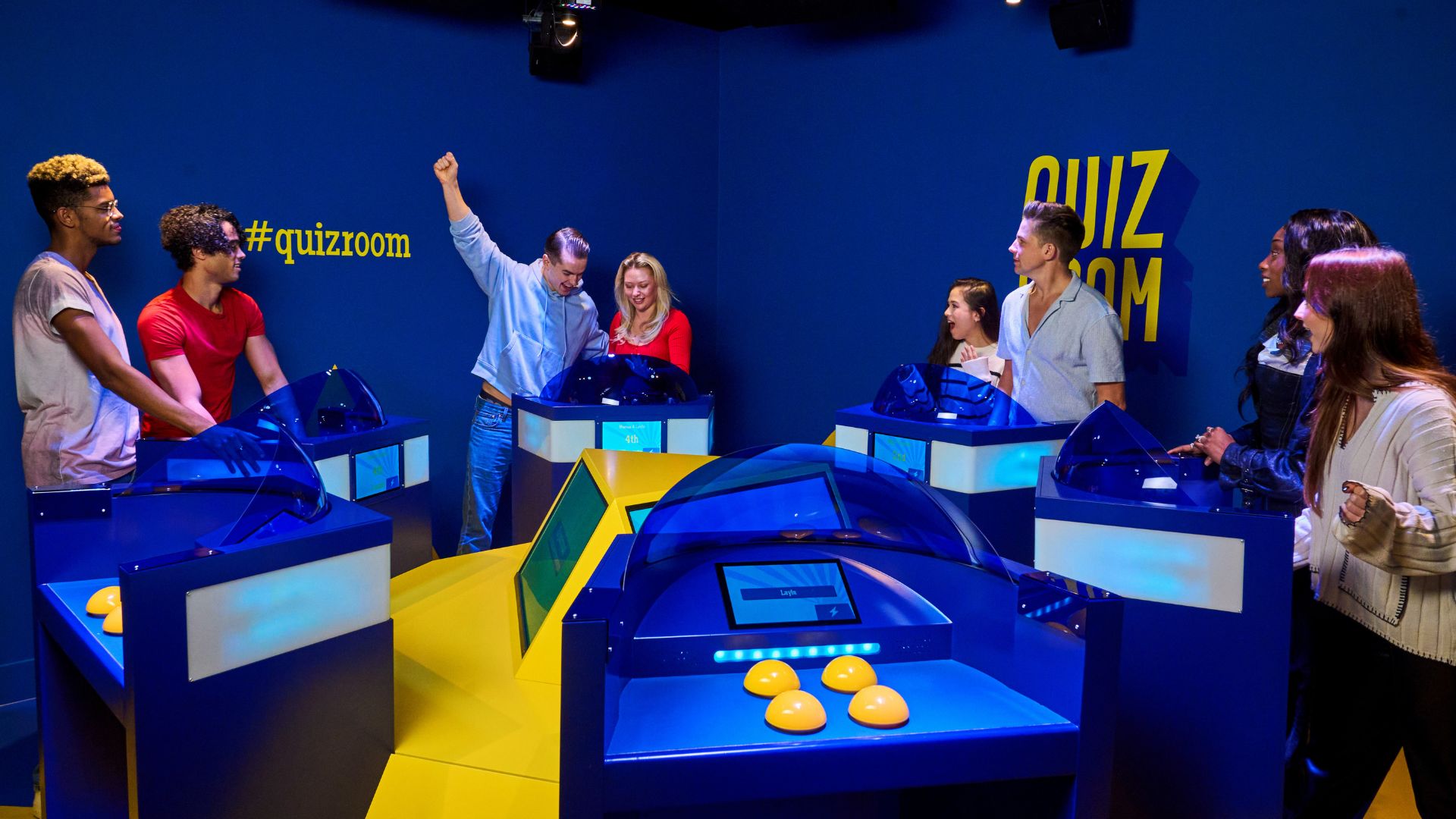people stood at podiums in groups of two, smiling and cheering playing a game