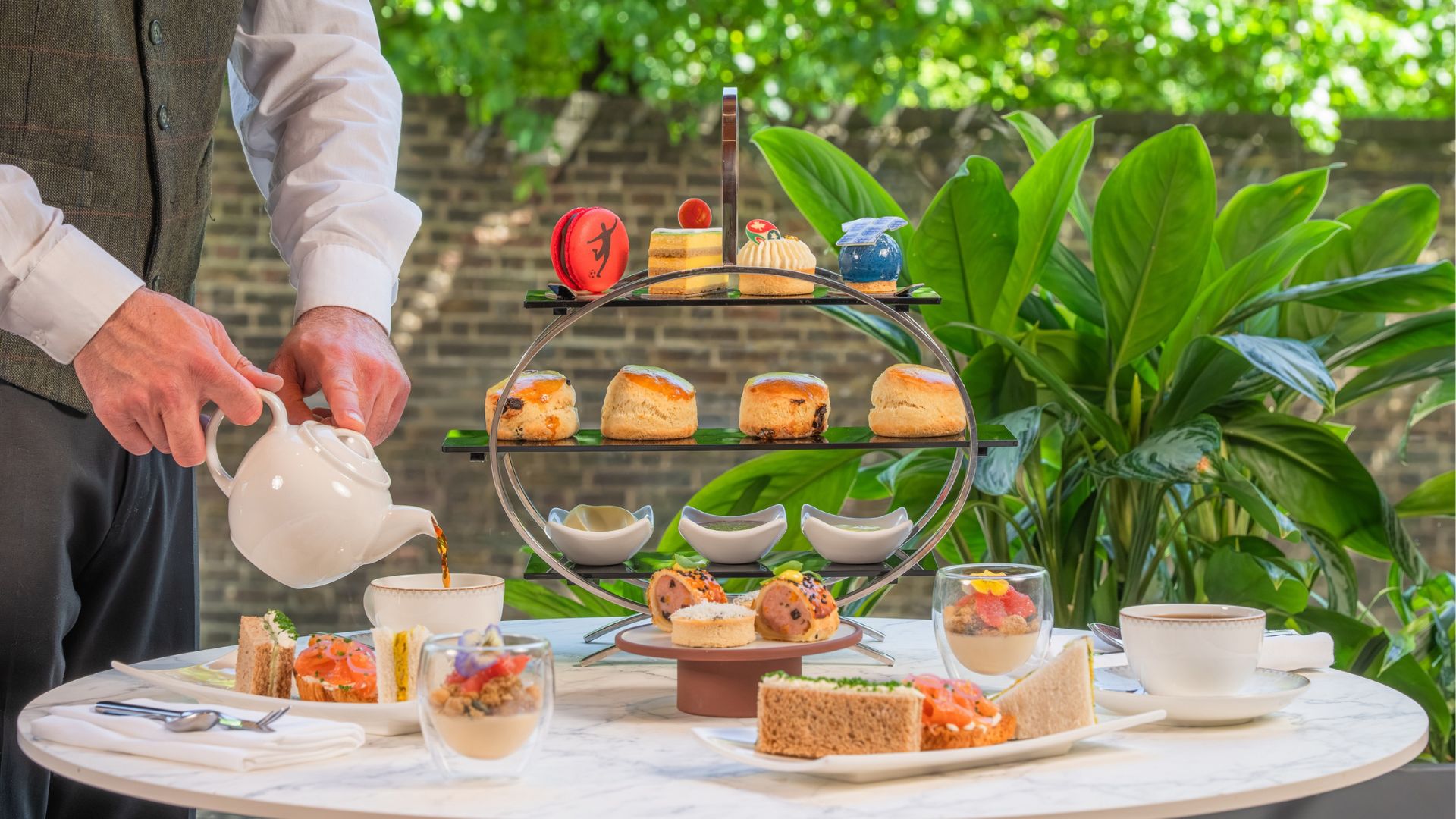 The Beautiful Game Afternoon Tea with football theme on table with waiter pouring from a teapot.