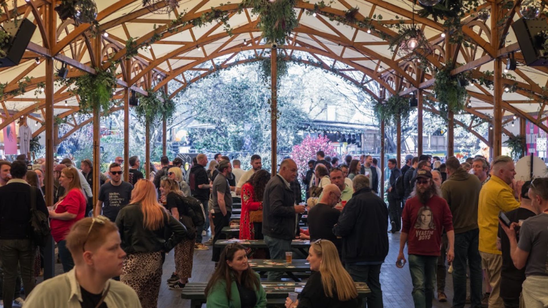 Raise a stein and soak up the atmosphere at BREW//LDN Oktoberfest, featuring craft beer, street food and live entertainment. Image courtesy of Pack Group. Visitors gather beneath a wooden pavilion decorated with greenery at BREW//LDN Oktoberfest, with communal tables and drinks throughout the venue.