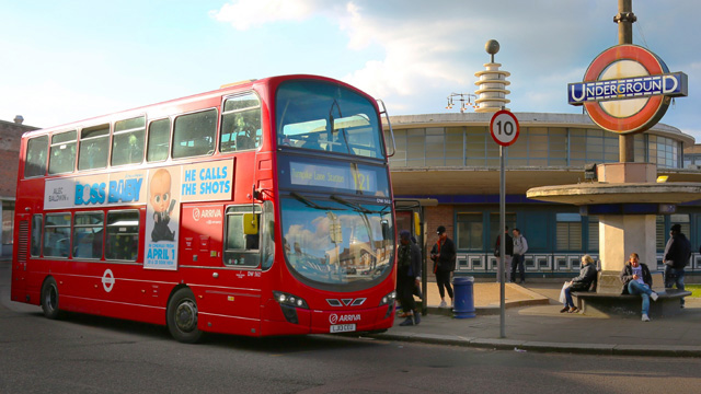 Les bus londoniens s'arrêtent à des points fixes de leur itinéraire © visitlondon.com / Antoine Buchet. Un bus rouge de Londres attend à l'arrêt de bus alors que les gens font la queue près d'une station de métro de Londres.