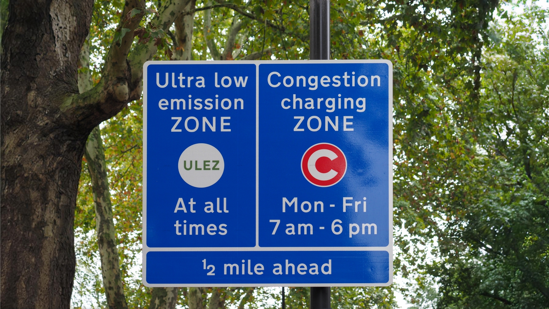 A photo of a road sign with details about the ULEZ and congestion charge zones in London