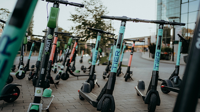 Séries de trottinettes électriques garées sur le trottoir.