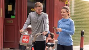 Un homme sur un vélo Santander se tient à côté d'une femme regardant l'écran de son smartphone à Londres