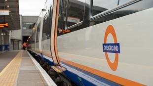A photo of the side of an orange London overground train on a platform