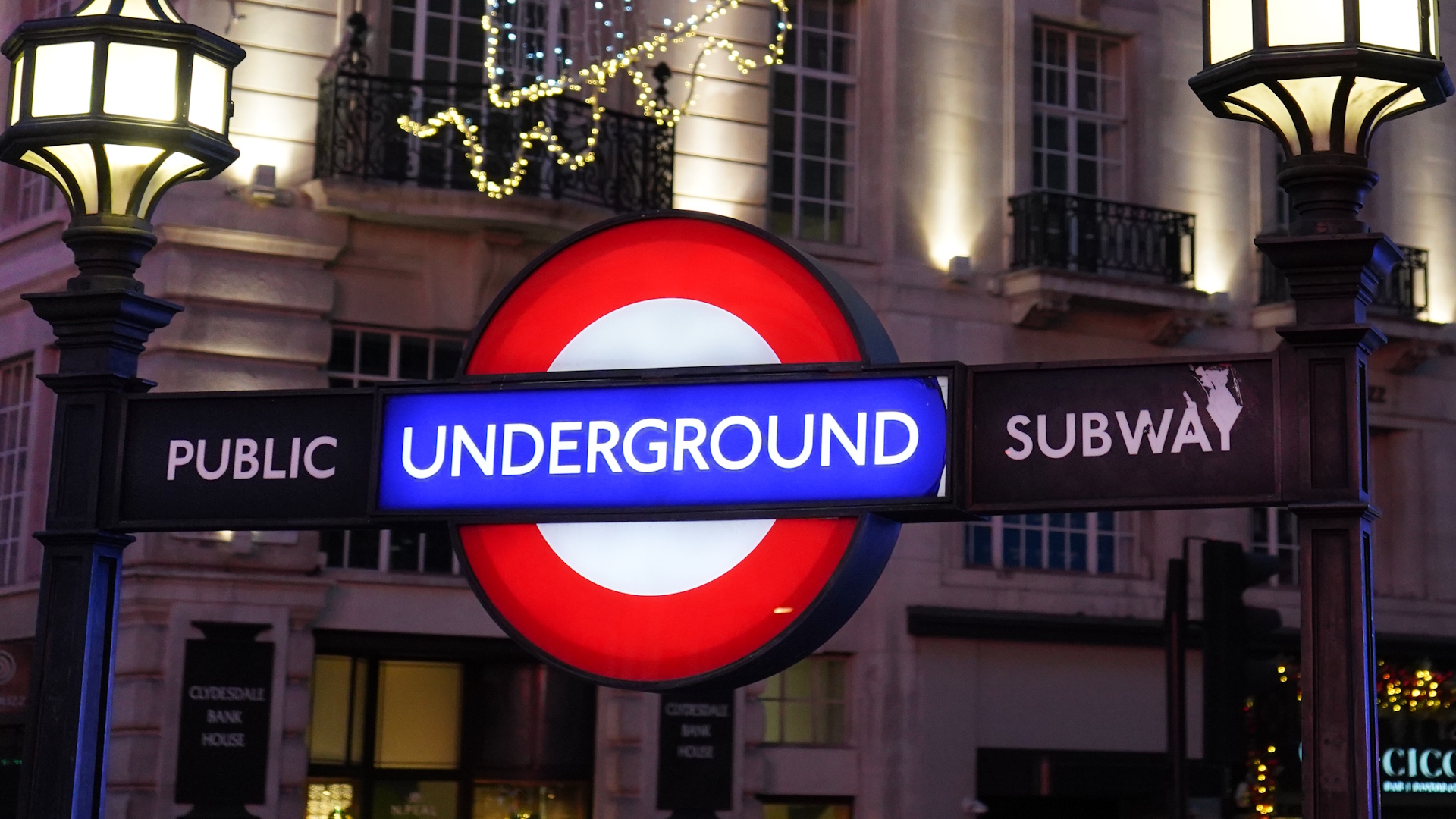 Illuminated London Underground roundel at night at a Tube station.
