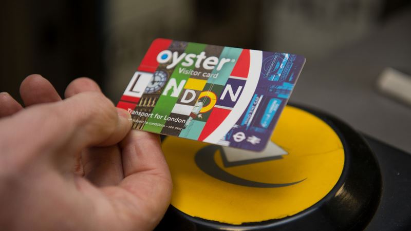 A photo of someone's hand tapping a London visitor Oyster card onto a Tube gate reader