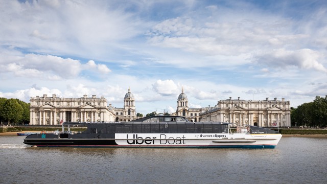 Gleite mit Uber Boat von Thames Clippers an Wahrzeichen vorbei. Bild mit Genehmigung von Uber Boat von Thames Clippers. Das Uber Boat von Thames Clippers Flussboot gleitet die Themse entlang und am Old Royal Naval College vorbei.