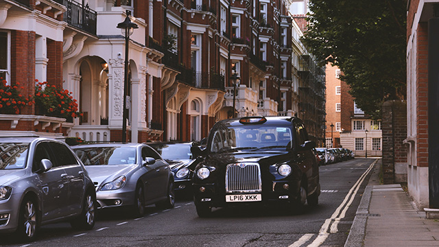 Taxi noir de Londres, Photo par Arvydas Venckus sur Unsplash Un taxi noir roule dans une rue de Londres avec d'autres voitures garées sur le côté.