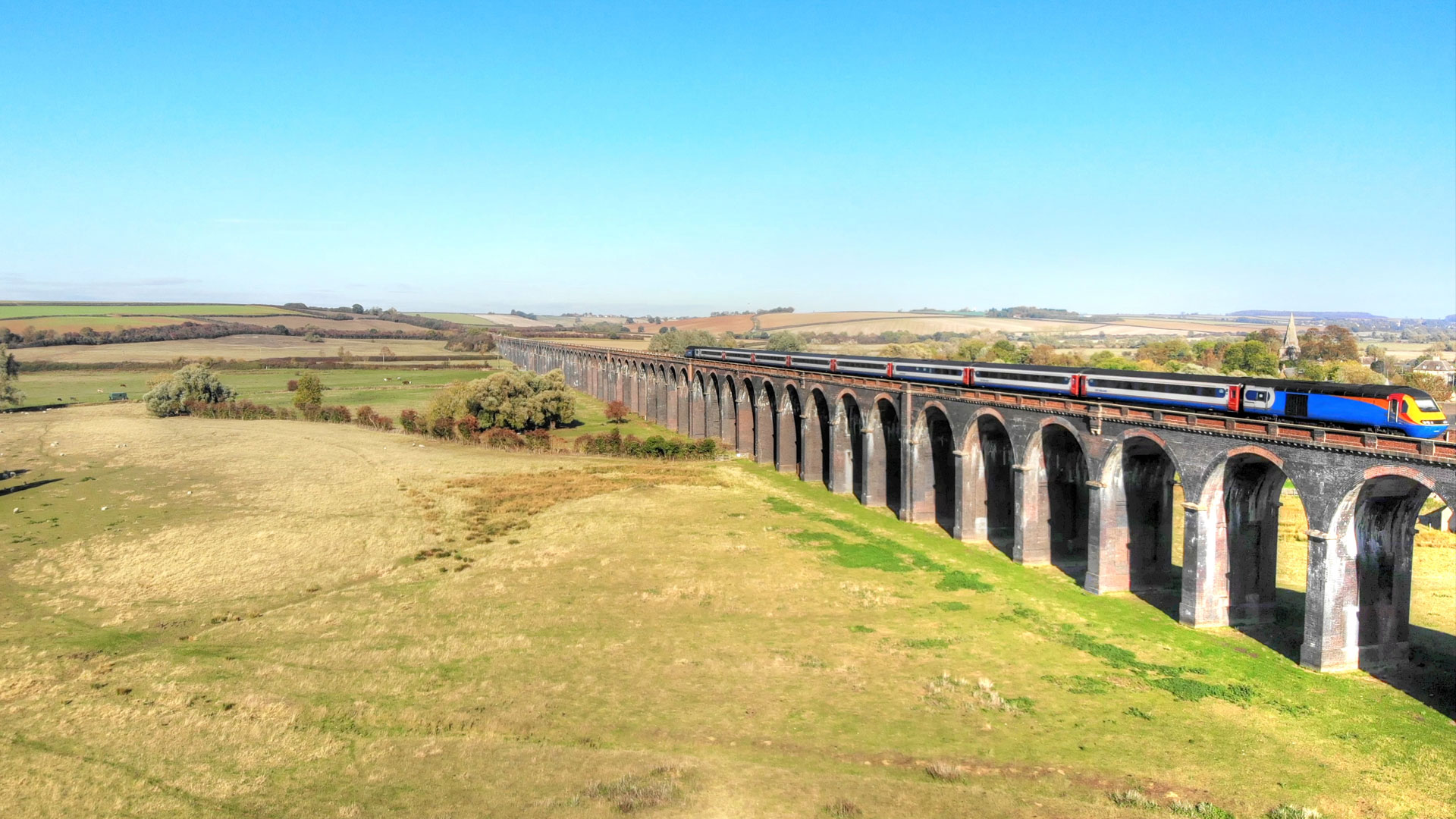 Blue, white and red train whizzing past the green English countryside.