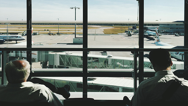 Deux personnes regardant les avions passer à l'aéroport d'Heathrow, Photo par Robert Bye sur Unsplash Deux passagers sont assis en regardant des avions sur la piste de l'aéroport d'Heathrow.