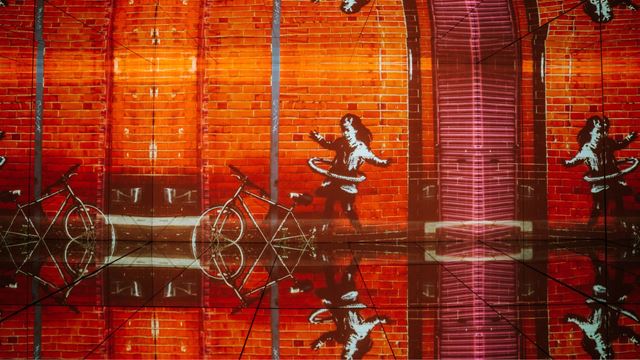 Orange background with Banksy graphics in immersive room with floor to ceiling projections.