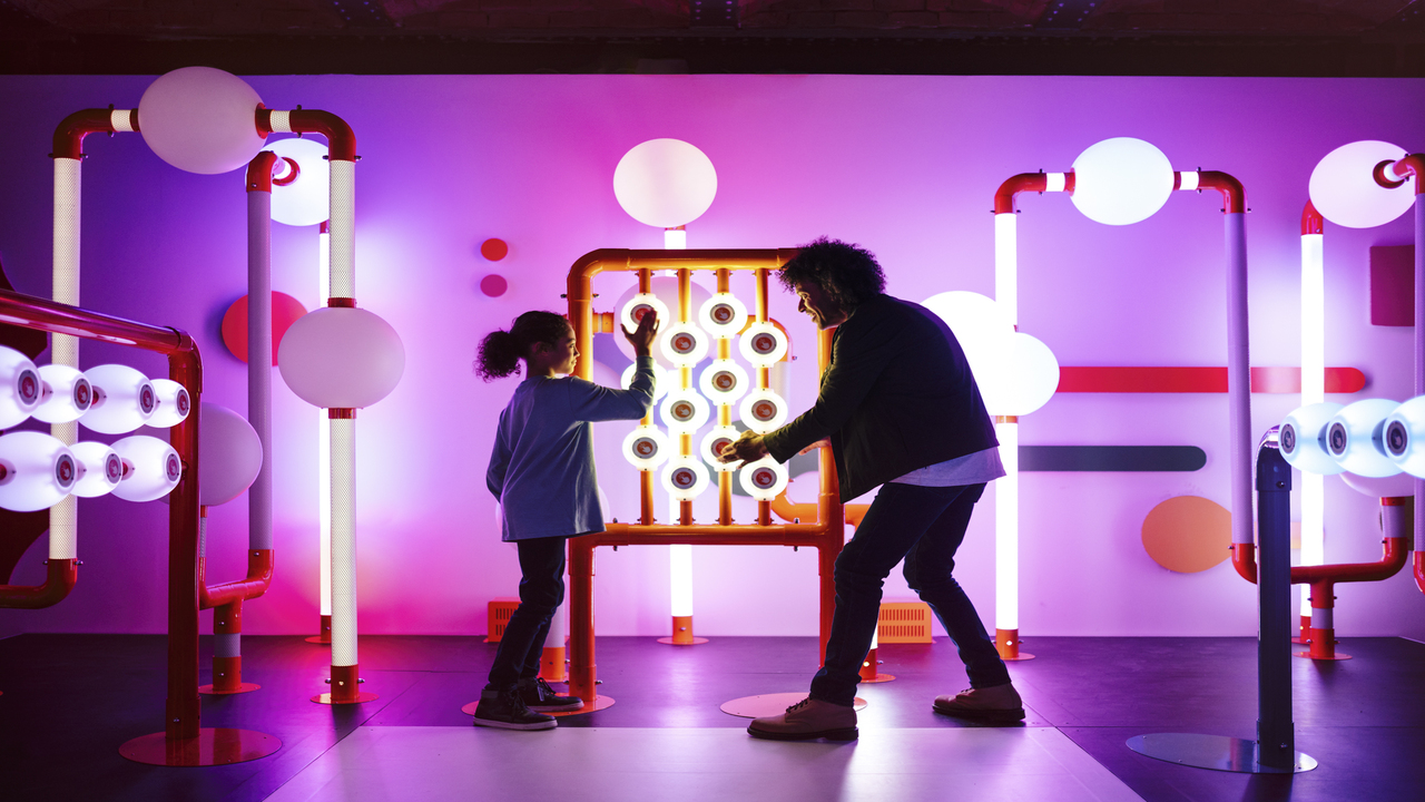 Un homme et une jeune fille joue de la musique dans une pièce violette au Science Museum.