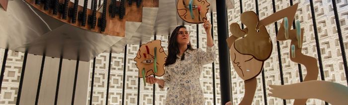 A woman hold up wodden art pieces art London Design Festival.