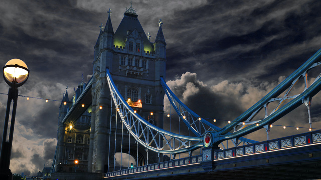 Die Tower Bridge vor dunkler Kulisse mit dunklen Wolken und hellblauem Geländer.