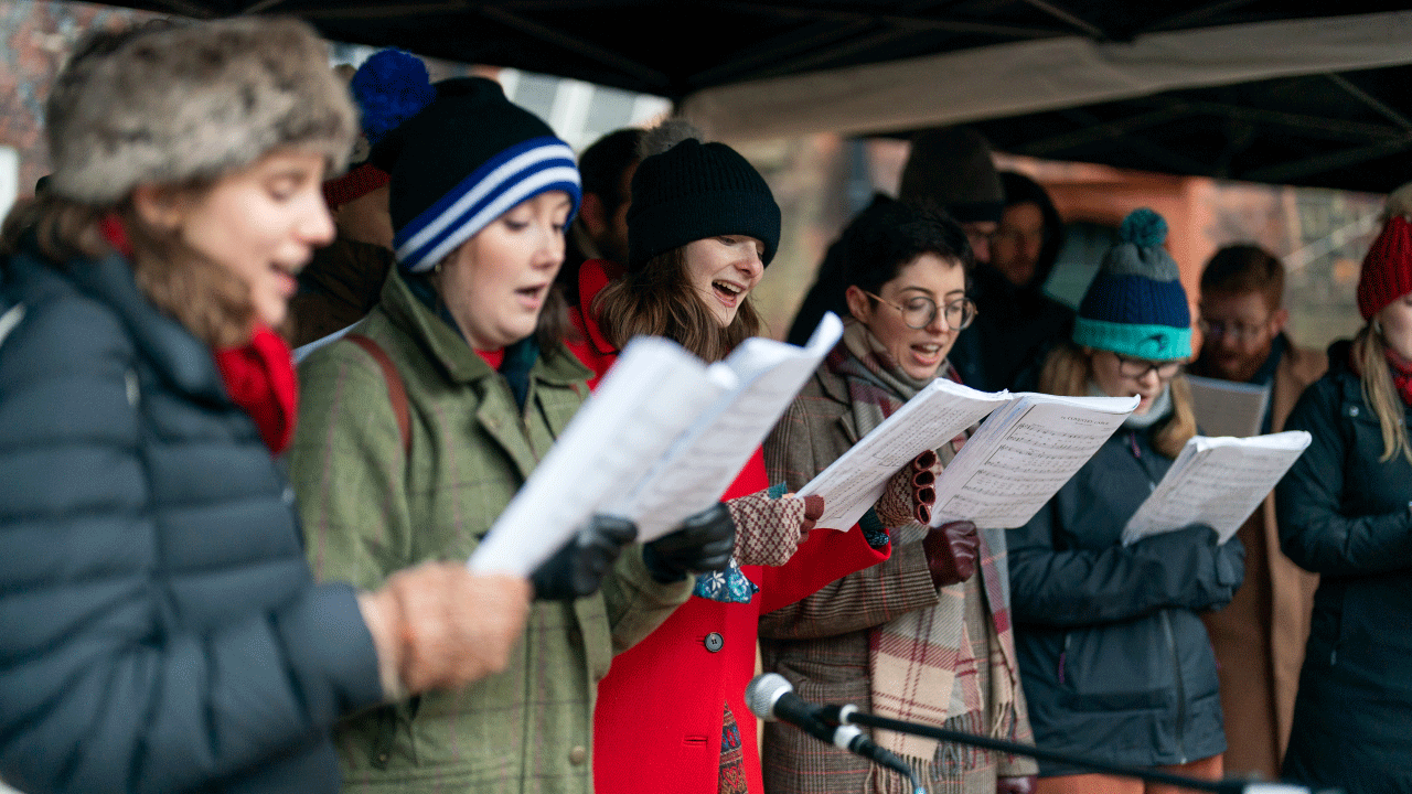 Revelers sing carols in Fulham Palace courtyard