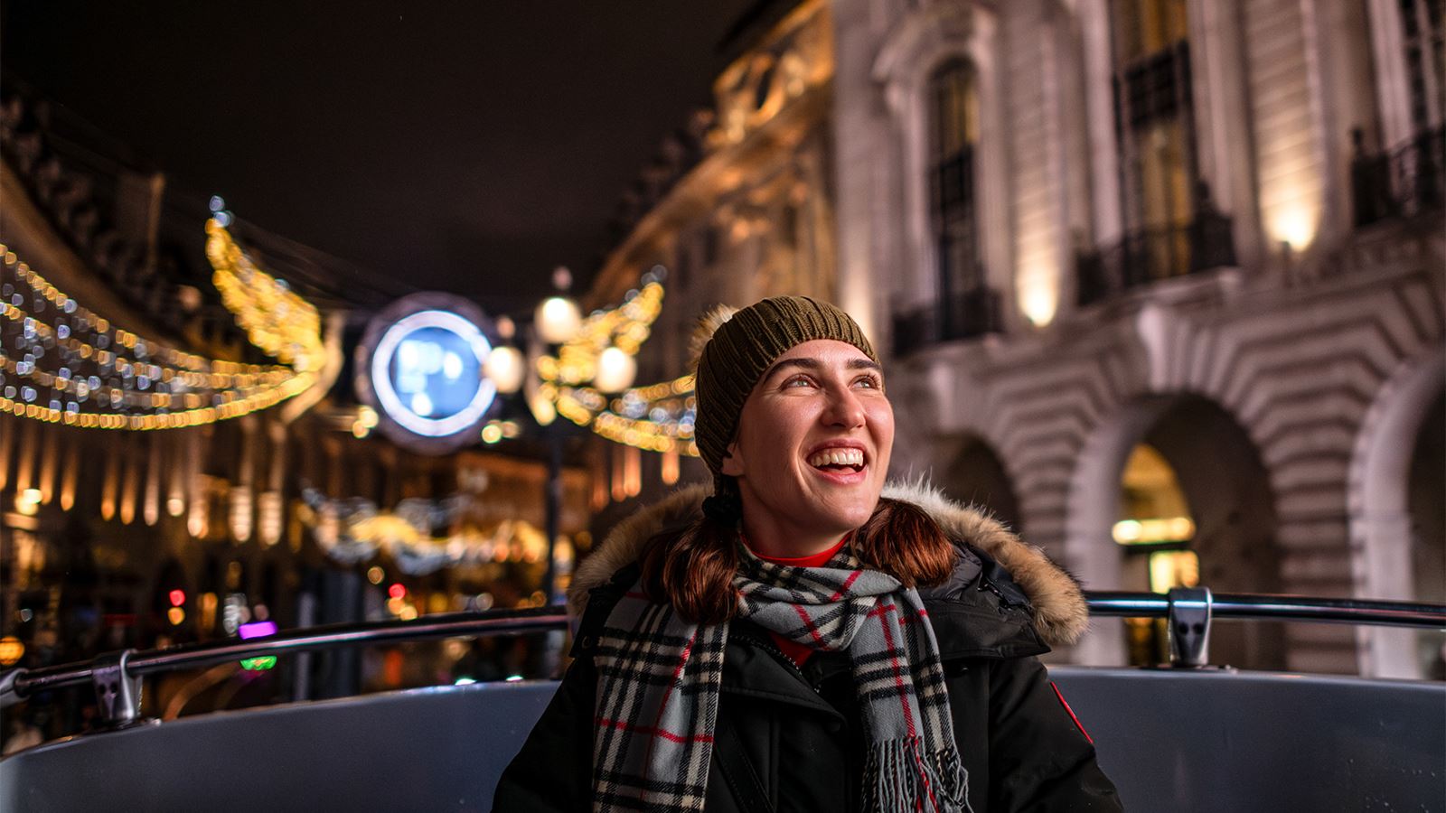 A young lady wrapped up warm enjoying the festive lights from a bus tour.
