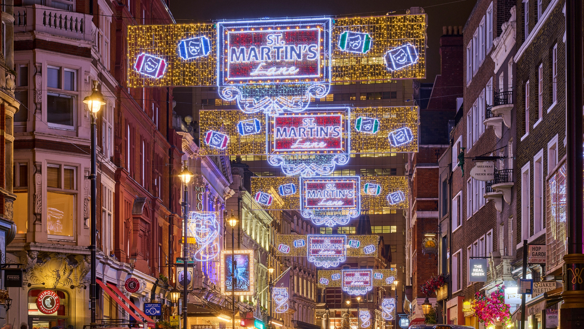 Rows of LED Christmas lights hang above St Martin's Lane with St Martin's Lane written on each with symbols paying homage to the theatre of the area