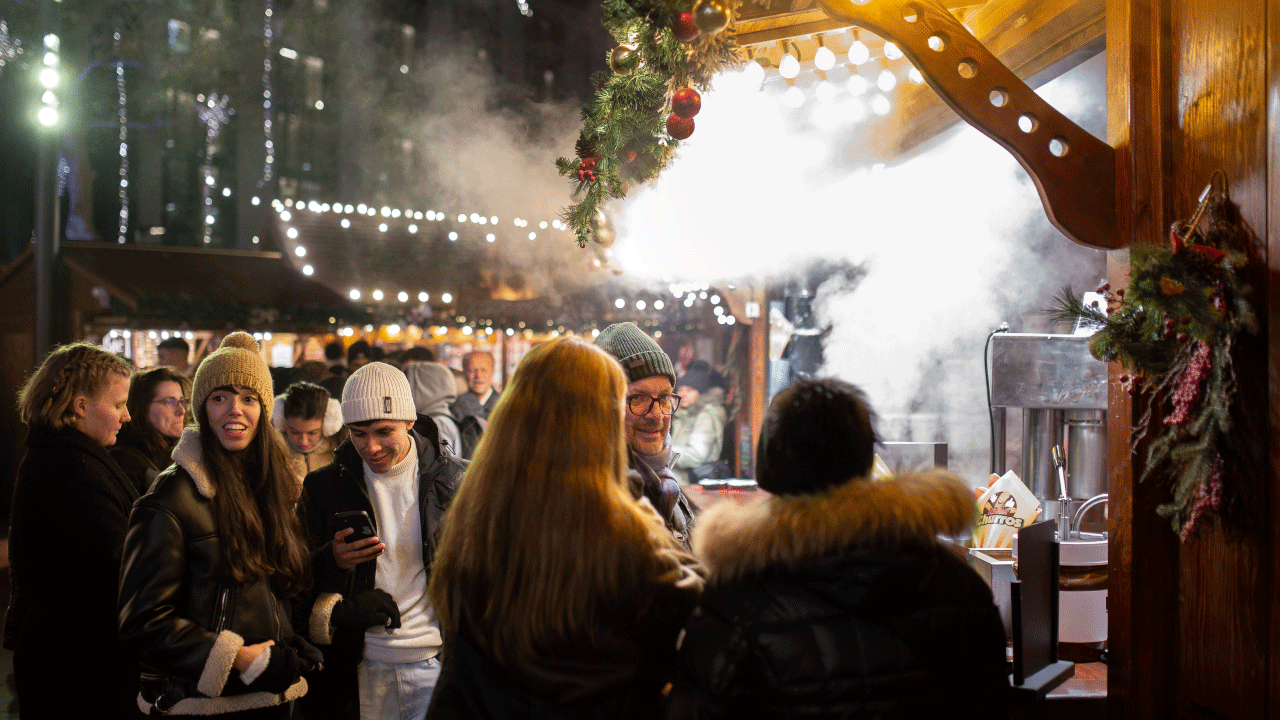 Crowds of people flock around a food vendor at Leicester Square Christmas market