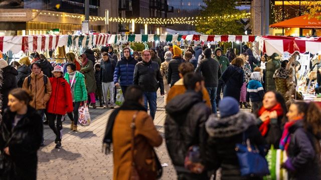 A photo of people walking around Wembley Park Christmas market with stalls and Christmas lights dotted around the area