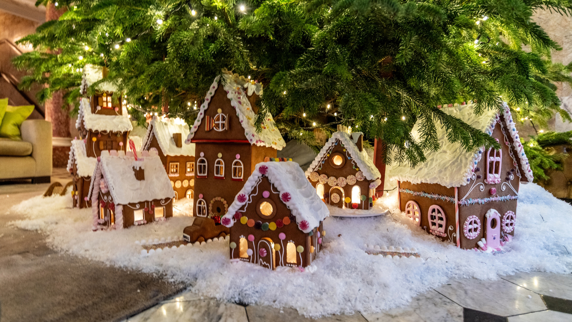 A photo of edible light up gingerbread houses beneath the Christmas tree at The London EDITION
