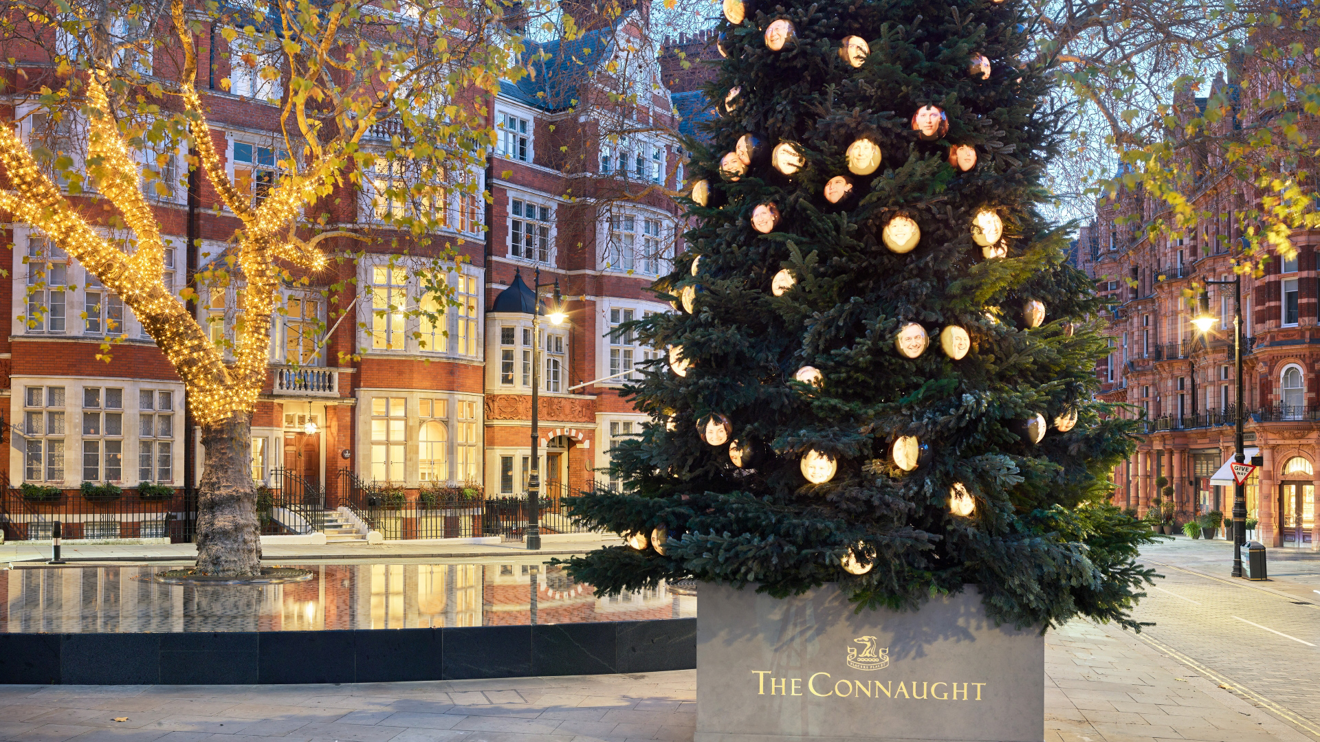 A photo of the Christmas tree stood outside The Connaught hotel covered in light up baubles with photos of different AI-generated faces