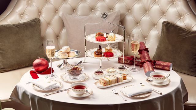 Une table ronde où sont disposés de nombreuses assiettes avec sandwichs et petits gâteaux.