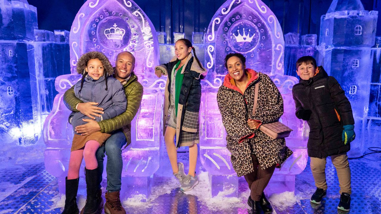 Don't miss out on an adventure along the ice trail at the Kingdom of Winter. Image courtesy of Mance Communications. A family sit on thrones of ice at the kingdom of winter in london.