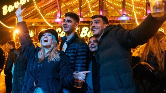 Eine Gruppe von Personen singen bei Live Musik in der Bavarian Bar im Winter Wonderland in London mit. 