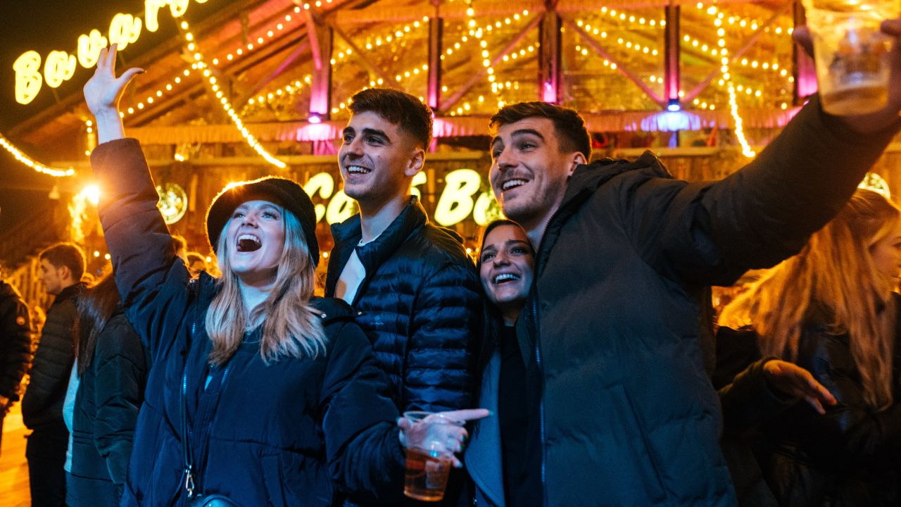 People cheer and dance by the bavarian  bar at winter wonderland.