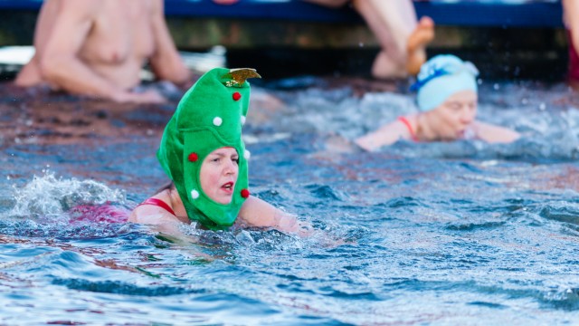 La coupe Peter Pan du jour de Noël à Hyde Park. Image fournie par la Serpentine Swimming Club. Une femme porte un ornement vert ressemblant à un sapin de Noël sur la tête pendant qu'elle se baigne.