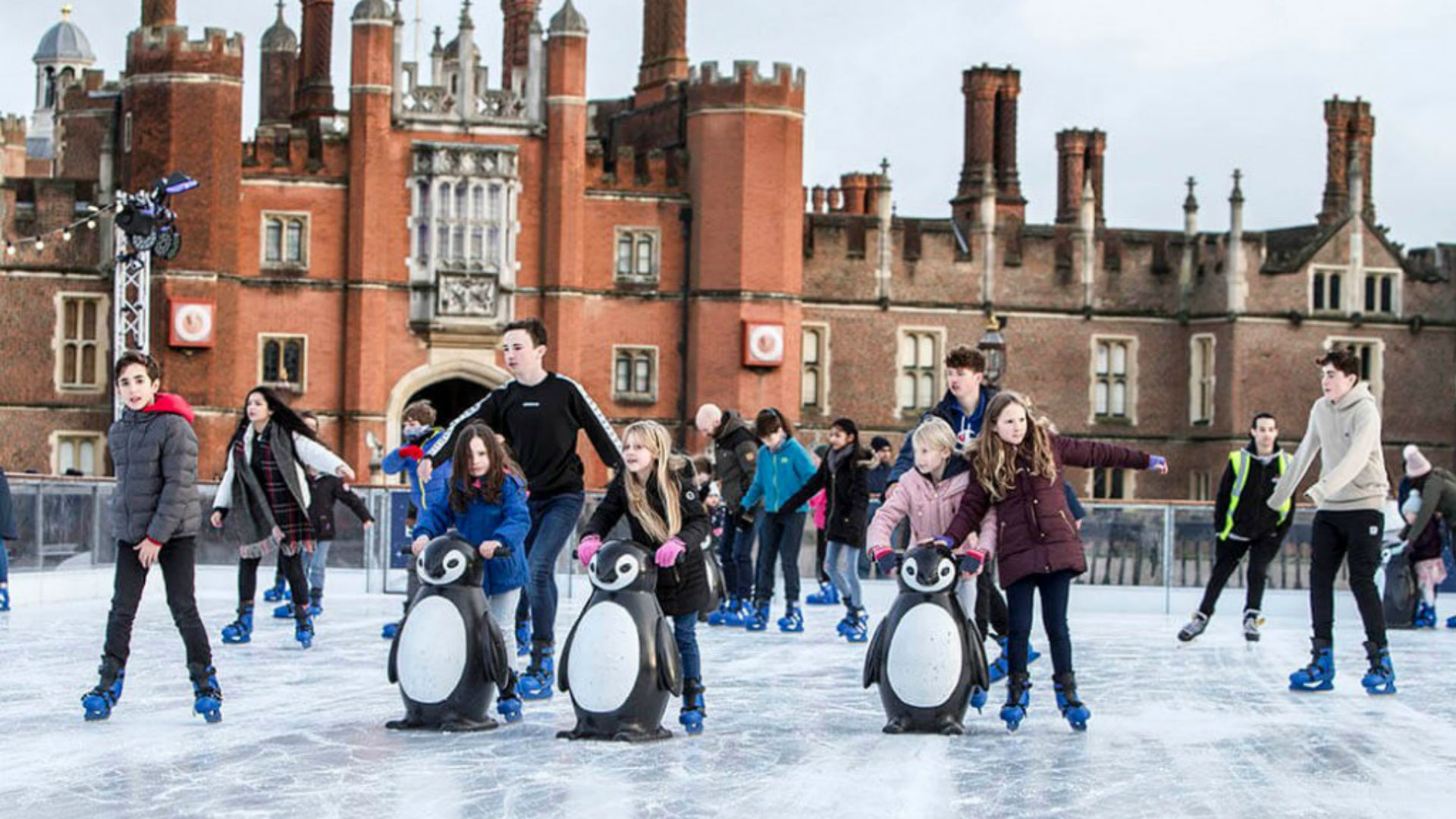 Hampton Court Palace Ice Rink. Image courtesy of Hampton Court Palace. A photo of families skating at the Hampton Court Palace Ice Rink, with the palace in the background.