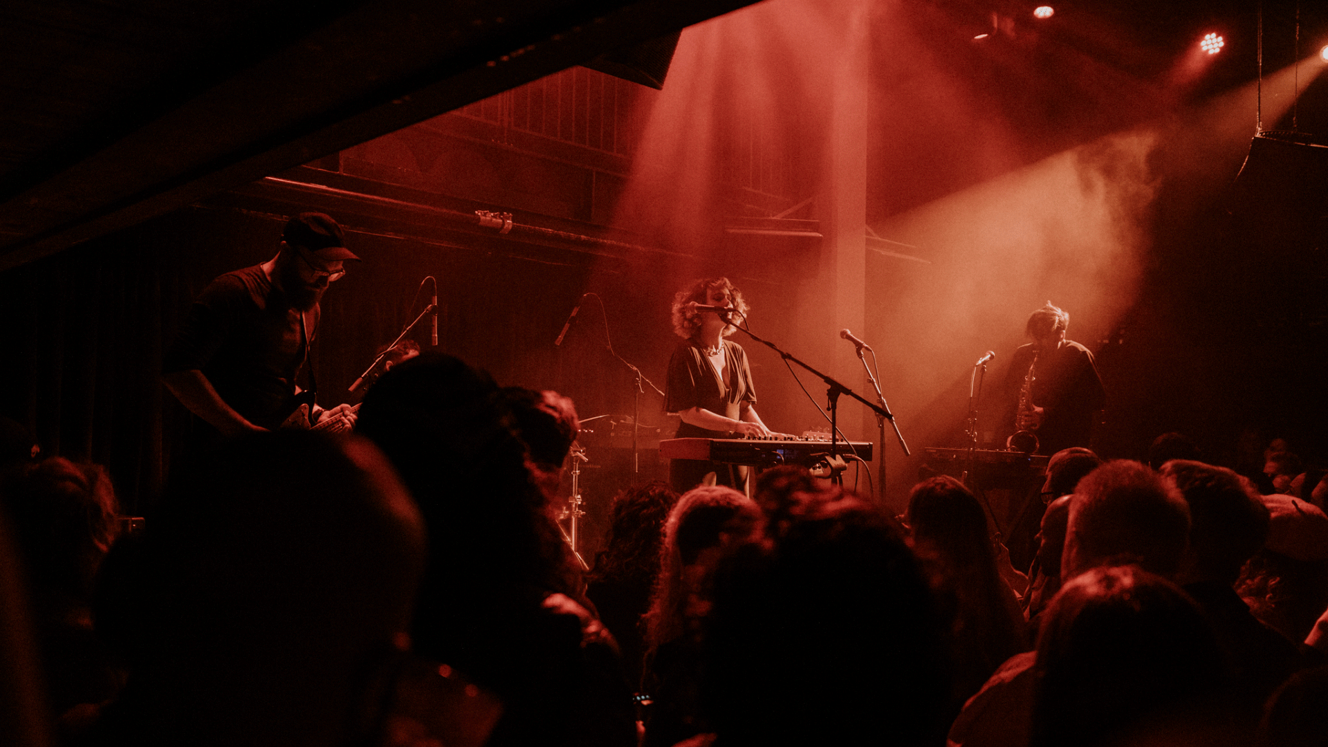 A sea of red illuminates the crowd and female singer whilst she plays piano