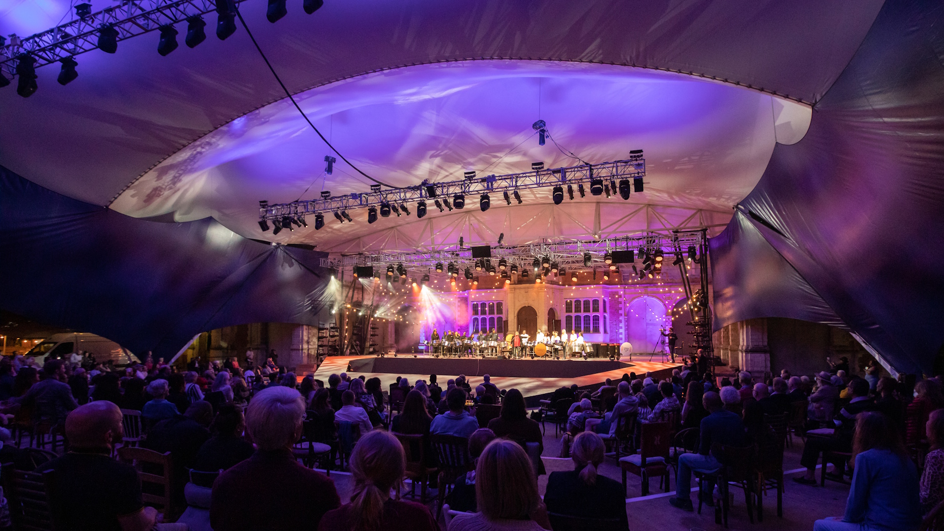 Lights illuminate the stage in front of a big audience at Opera Holland Park, London.