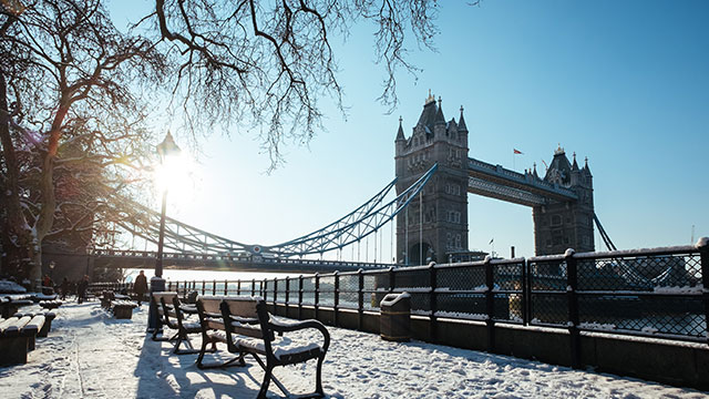 Tower Bridge am Weihnachtstag im Schnee © Robert Bye / Unsplash. Bild mit Genehmigung von Robert Bye / Unsplash. Die Tower Bridge und der umliegende Gehweg im Schnee an einem sonnigen Weihnachtstag