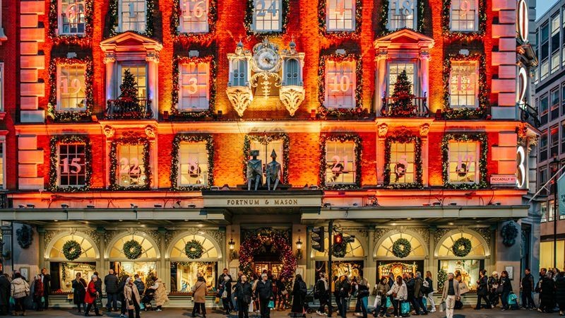 Admire the festive decorations adorning stores such as Fortnum and Mason at Christmas. Credit: Michael Barrow/London & Partners. Image courtesy of London & Partners. Bright red and gold lights illuminate the front of Fortnum and Mason with each window representing an advent calendar door