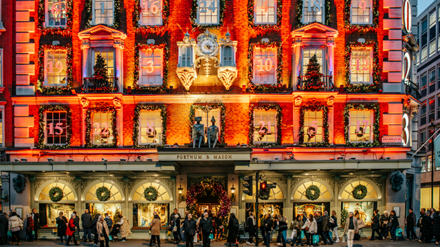 Bright red and gold lights illuminate the front of Fortnum and Mason with each window representing an advent calendar door