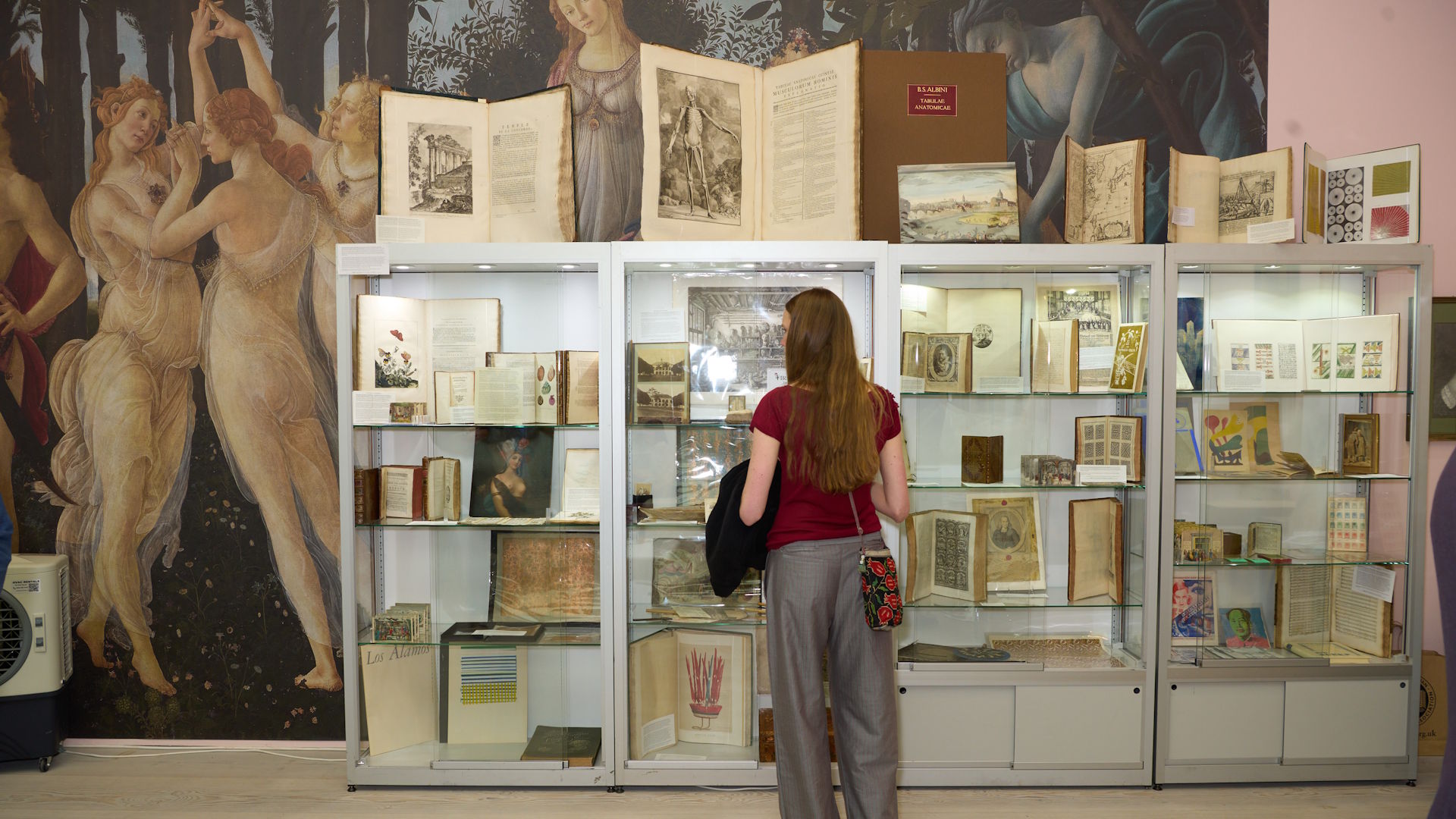 A person studies books and manuscripts in a display case at Firsts: London’s Rare Book Fair.