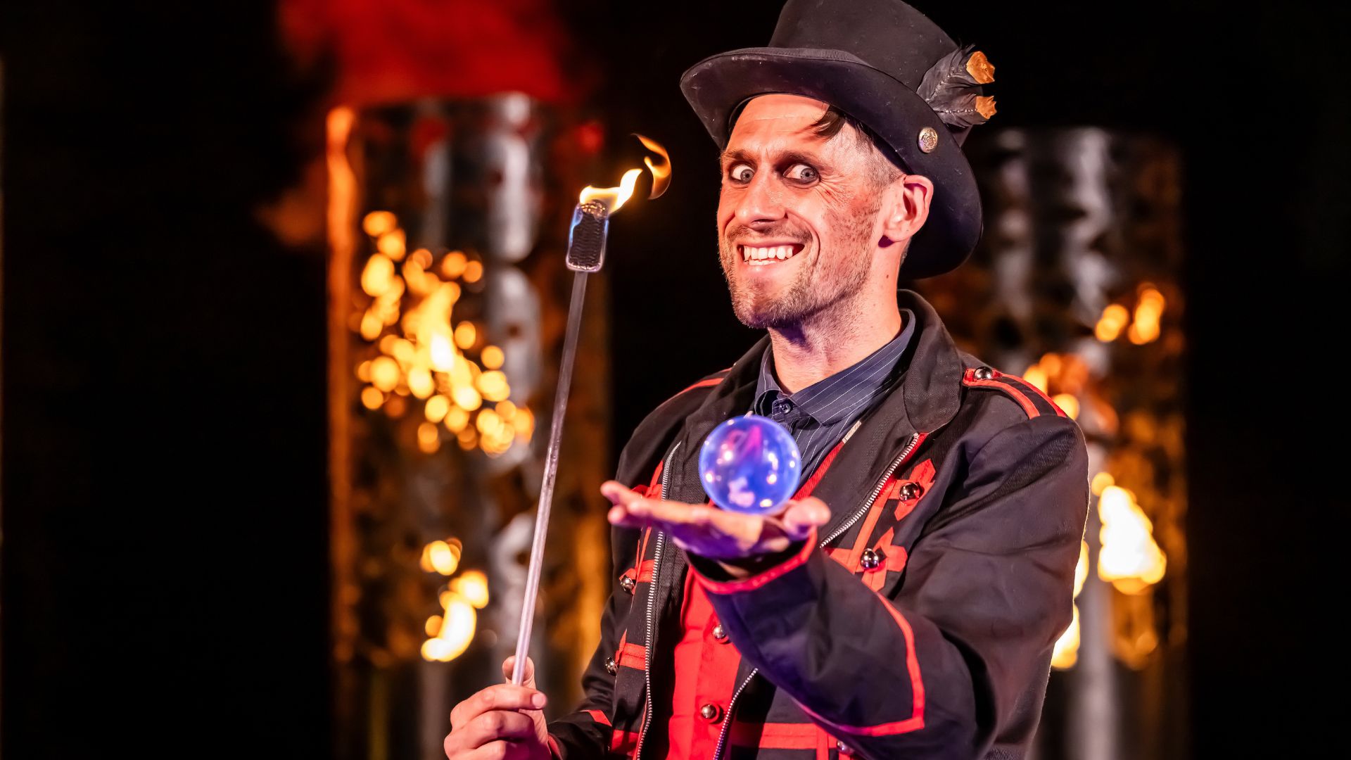 A costumed magician holds a glowing crystal ball on the Halloween at Kew trail at night.