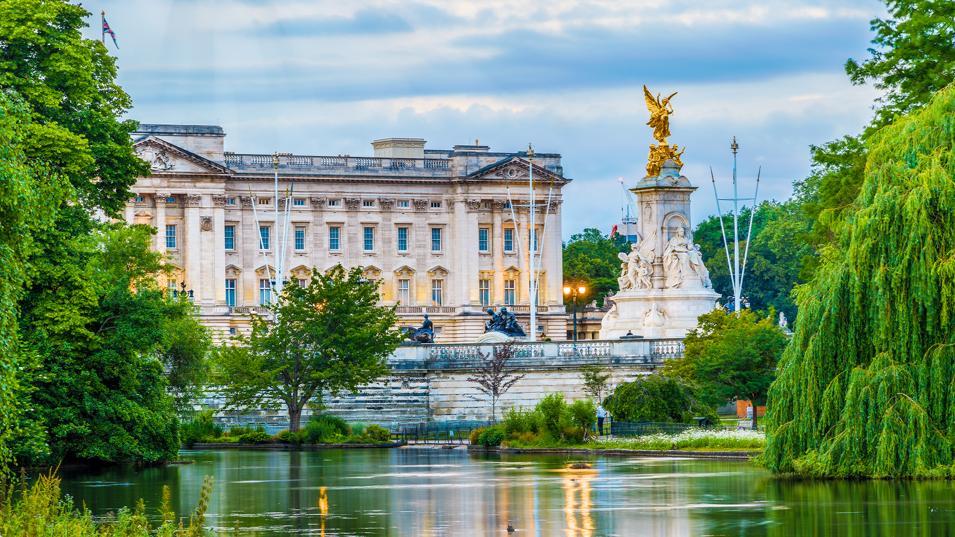 Buckingham Palace behind a lake on a cloudy day in London.