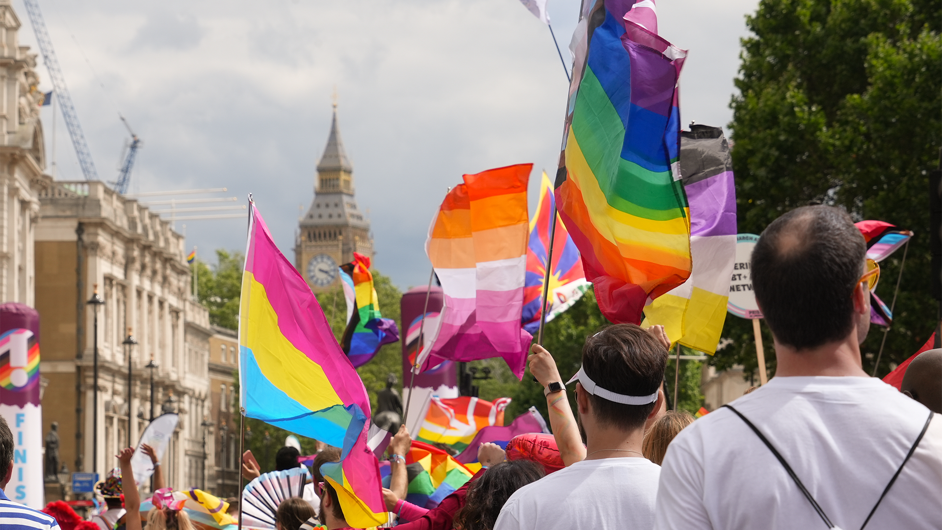 Feiern Sie den Pride auf den Straßen Londons bei der jährlichen Parade. Bildnachweis: Peter Cohen. Bild mit freundlicher Genehmigung von London & Partners. Menschen schwenken während eines Pride-Umzugs in London regenbogenfarbene Fahnen.