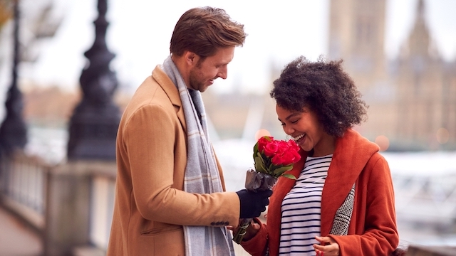 Ein Mann gibt einer Frau vor den Houses of Parliament Blumen am Valentinstag in London.