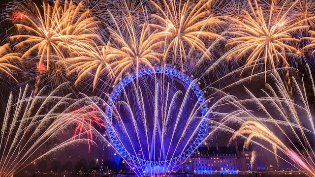 Verabschiede dich mit einem großartigen Silvesterfeuerwerk vom Jahr. Bild mit Genehmigung von Shutterstock. Silvesterfeuerwerk das in London as die Nacht erhellt, hinter dem blau leuchtenden London Eye