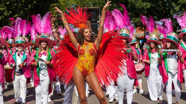 Feiern Sie mit beim Londoner Notting Hill Carnival im August. Bild mit Genehmigung von Shutterstock. Eine Frau mit Flügeln aus Federn und einem Paillettenkostüm euf einer Parade während des Notting Hill Carnival in London