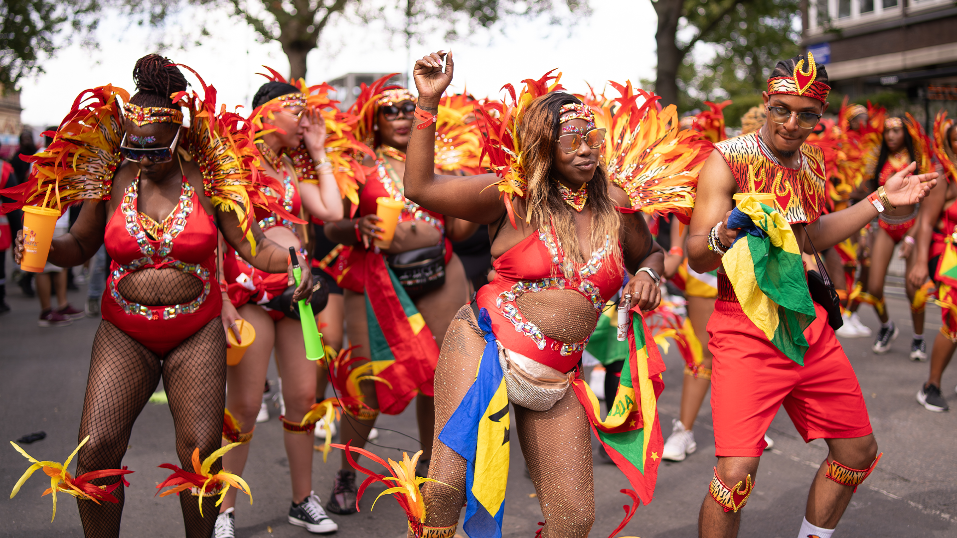 A group of carnival-goers with feathered wings and bright attire at Notting Hill Carnival