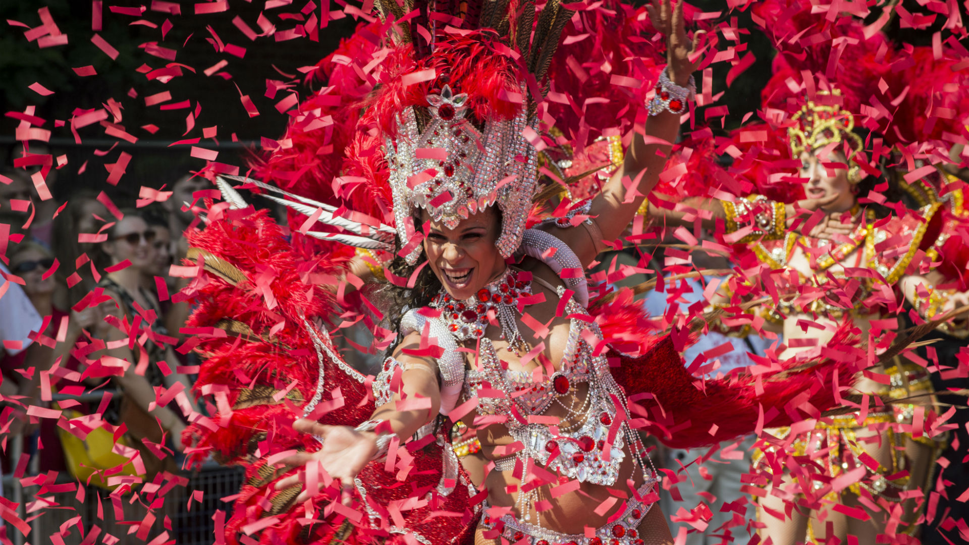Une reine du carnaval danse au carnaval de Notting Hill © Natasha108 via iStock. Avec l'aimable autorisation de Natasha108 via iStock. Une reine de carnaval vêtue d'un costume blanc avec des plumes rouges, entourée de rubans rouges, danse au carnaval de Notting Hill.