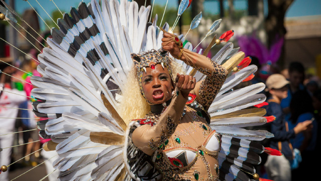 A woman in white feathers performing a dance during London's Notting Hill Carnival.